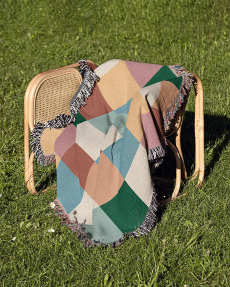 Soft woven throw blanket with a playful, colorful patchwork grid and fringe detail.
