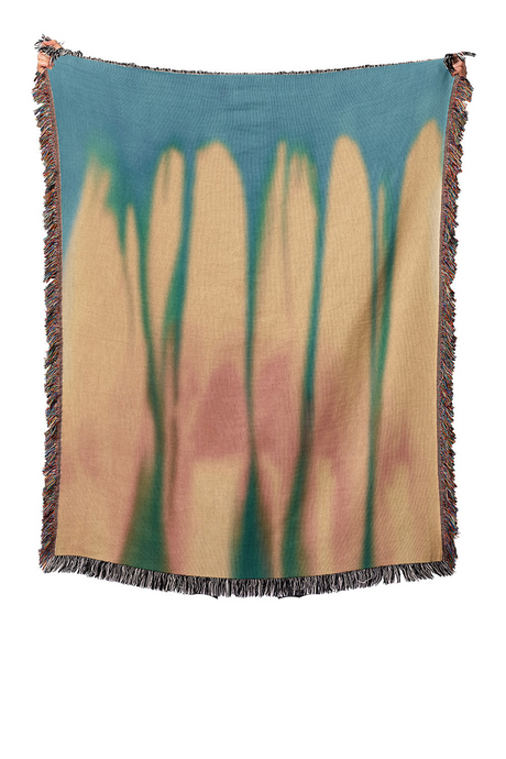 Woven blanket with abstract design of tall grasses on a blue background