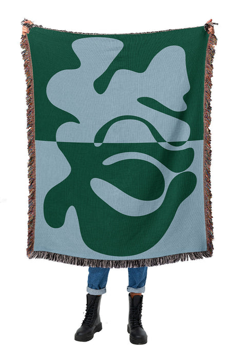 Blue and green woven throw blanket with an abstract organic design and modern aesthetic.
