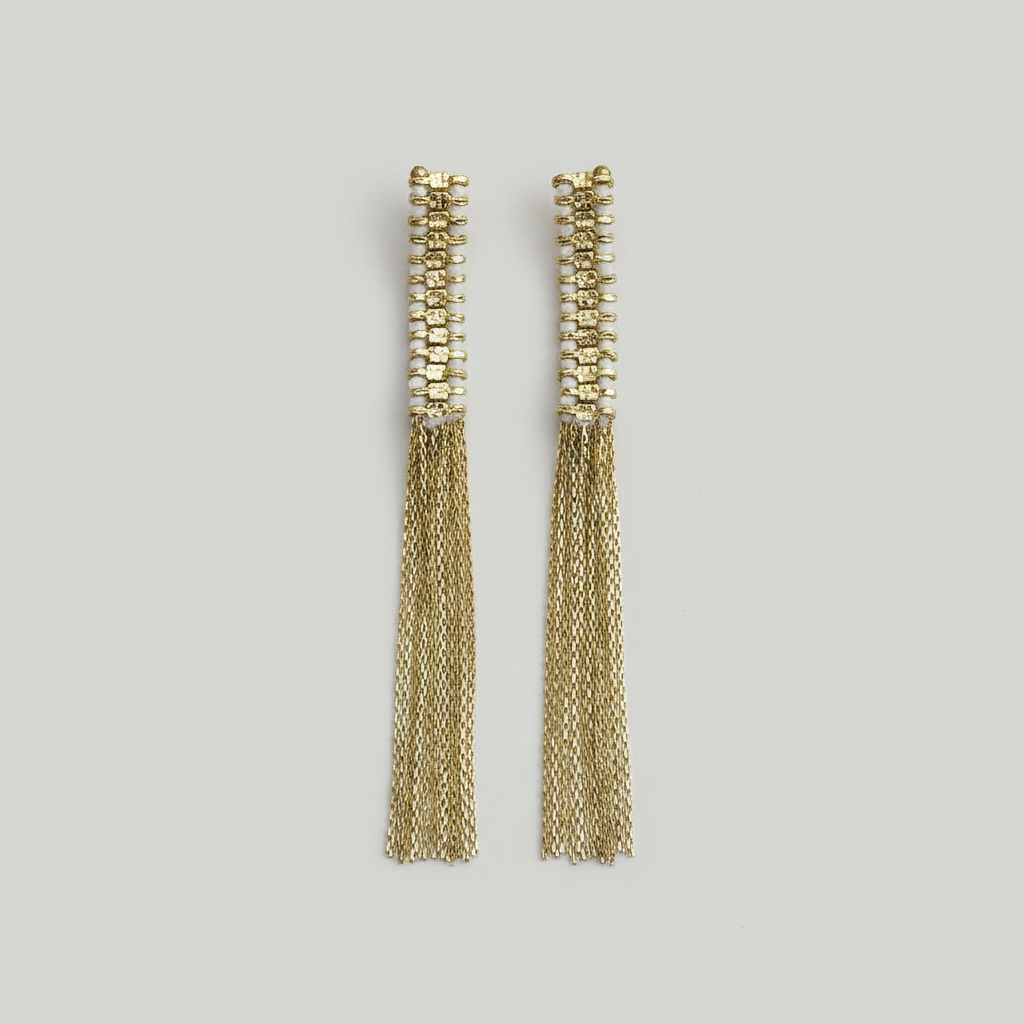 Pair of gold tassel earrings on a light gray background
