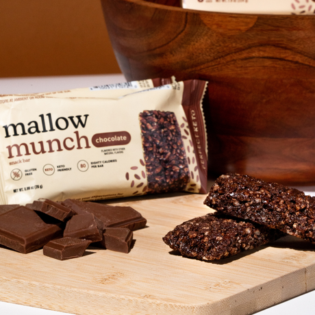 Mallow Munch chocolate bars on a wooden surface with packaging and chocolate pieces.