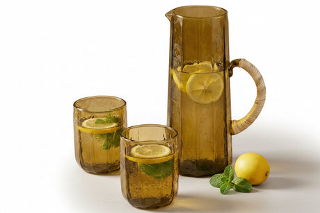 Brown glass pitcher and cups with lemon slices on a beige background