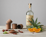 Bottle of Mezcal with ingredients on a wooden surface