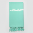 Mint green towel with white stripe and fringes on a light gray background