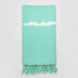 Mint green towel with white stripe and fringes on a light gray background