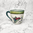 Ceramic mug with a colorful bird design on a marble surface