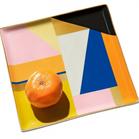 Colorful geometric-patterned tray with an orange on a white background
