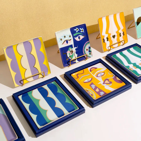 Collection of colorful abstract art trays on a light surface with a yellow wall background.