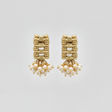 Gold earrings with pearl drops on a light gray background