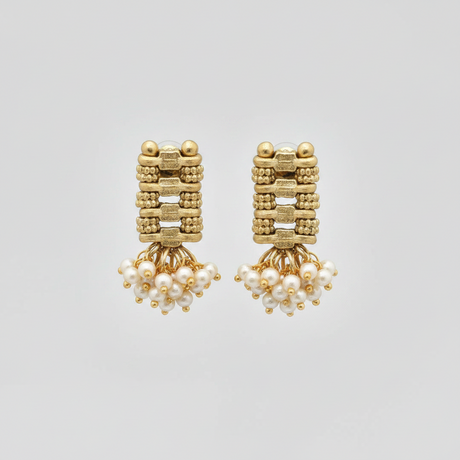 Gold earrings with pearl drops on a light gray background