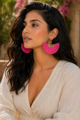 Woman wearing pink earrings and a white outfit with blurred background