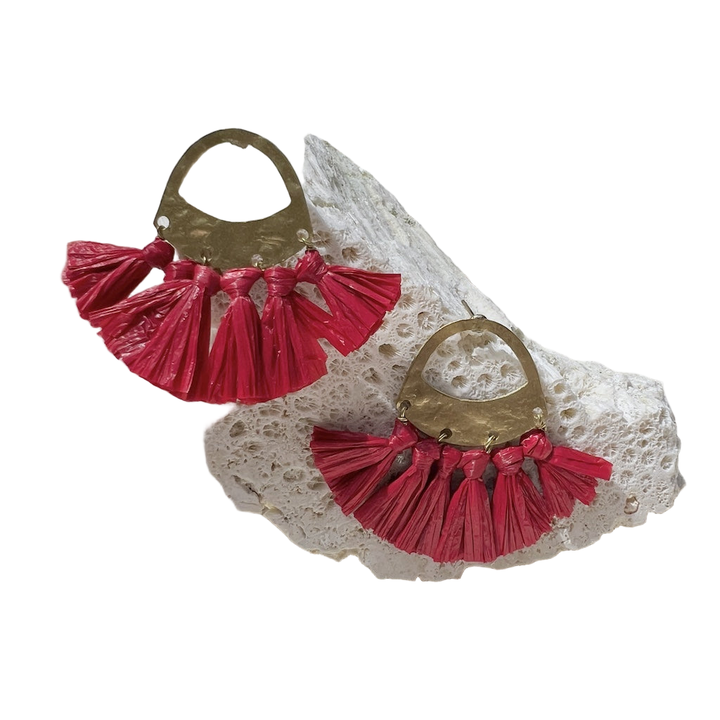 Pair of red tassel earrings on a textured white surface