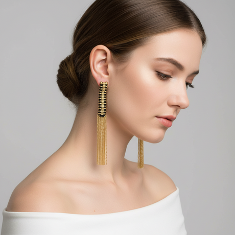 Woman wearing gold tassel earrings against a gray background