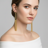 Woman wearing gold earrings against a gray background