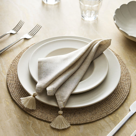 Table setting with beige plates, napkins, and placemat on a light surface.