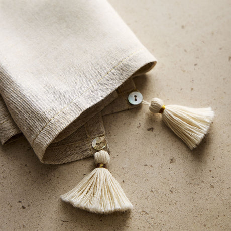 Beige fabric with tassels on a textured beige surface