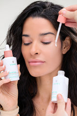 Woman applying skincare product to her face with a dropper.