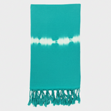 Teal towel with white tie-dye pattern and fringes on a light gray background