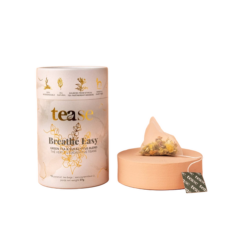 Tea packaging with a lid open, showing tea leaves and a teabag, on a white background.