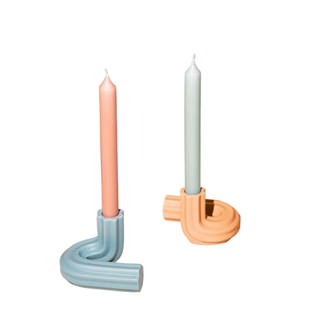 Two unique candle holders with candles on a white background