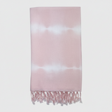 Pink and white tie-dye towel with fringes on a light gray background