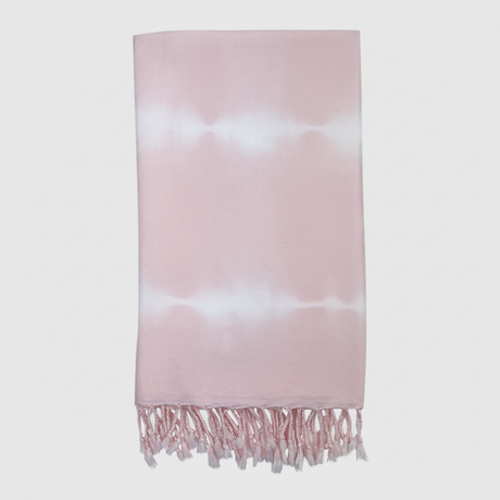 Pink and white tie-dye towel with fringes on a light gray background