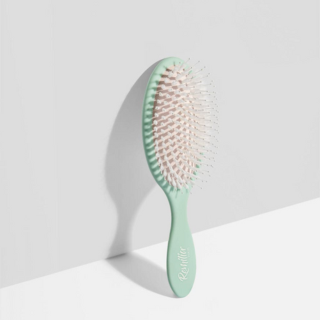 Mint green hairbrush with wooden bristles on a light gray background