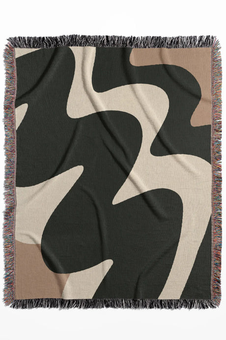 High-contrast cotton woven throw blanket featuring fluid shapes in black, off-white, and beige.
