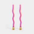 Two wavy, multicolored candles with gold bases on a light gray background
